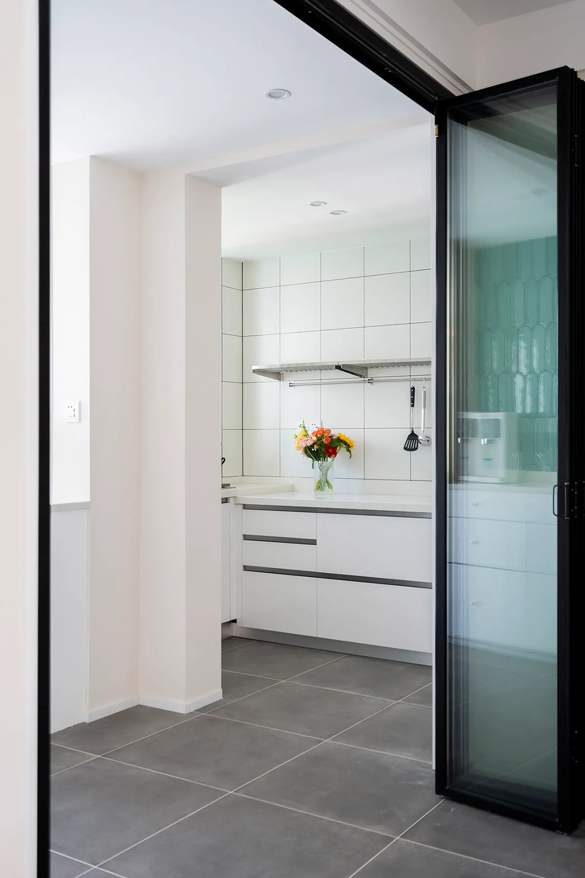 A modern kitchen with white tile cabinets and a sleek, minimalist design.