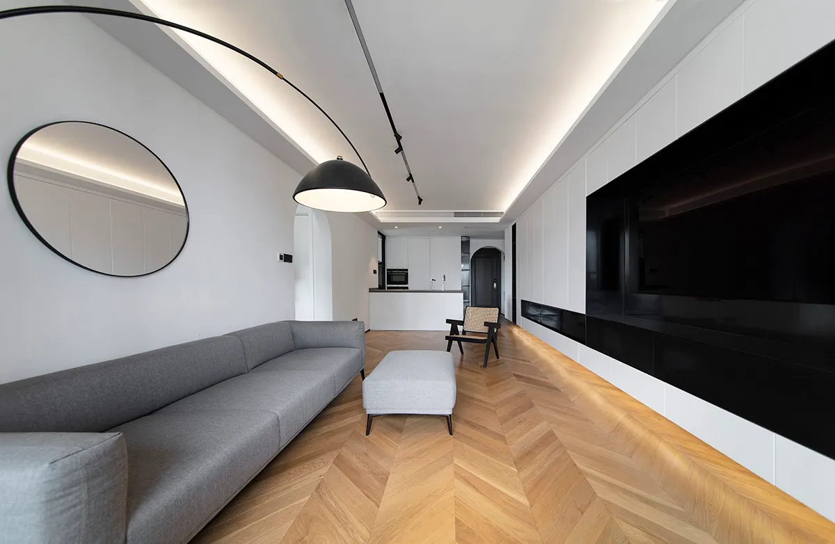 A modern minimalist living room featuring a wooden floor, metal accents, and glass elements.