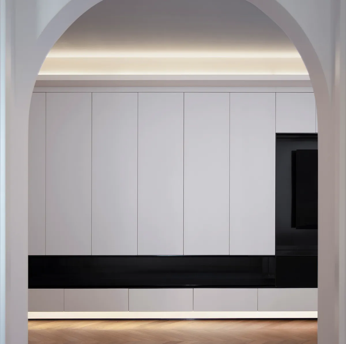 A minimalist white living room featuring modern white cabinets with a black base.