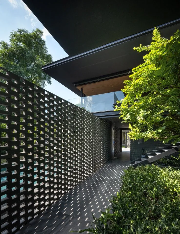 Modern building exterior featuring a metal lattice wall and lush greenery
