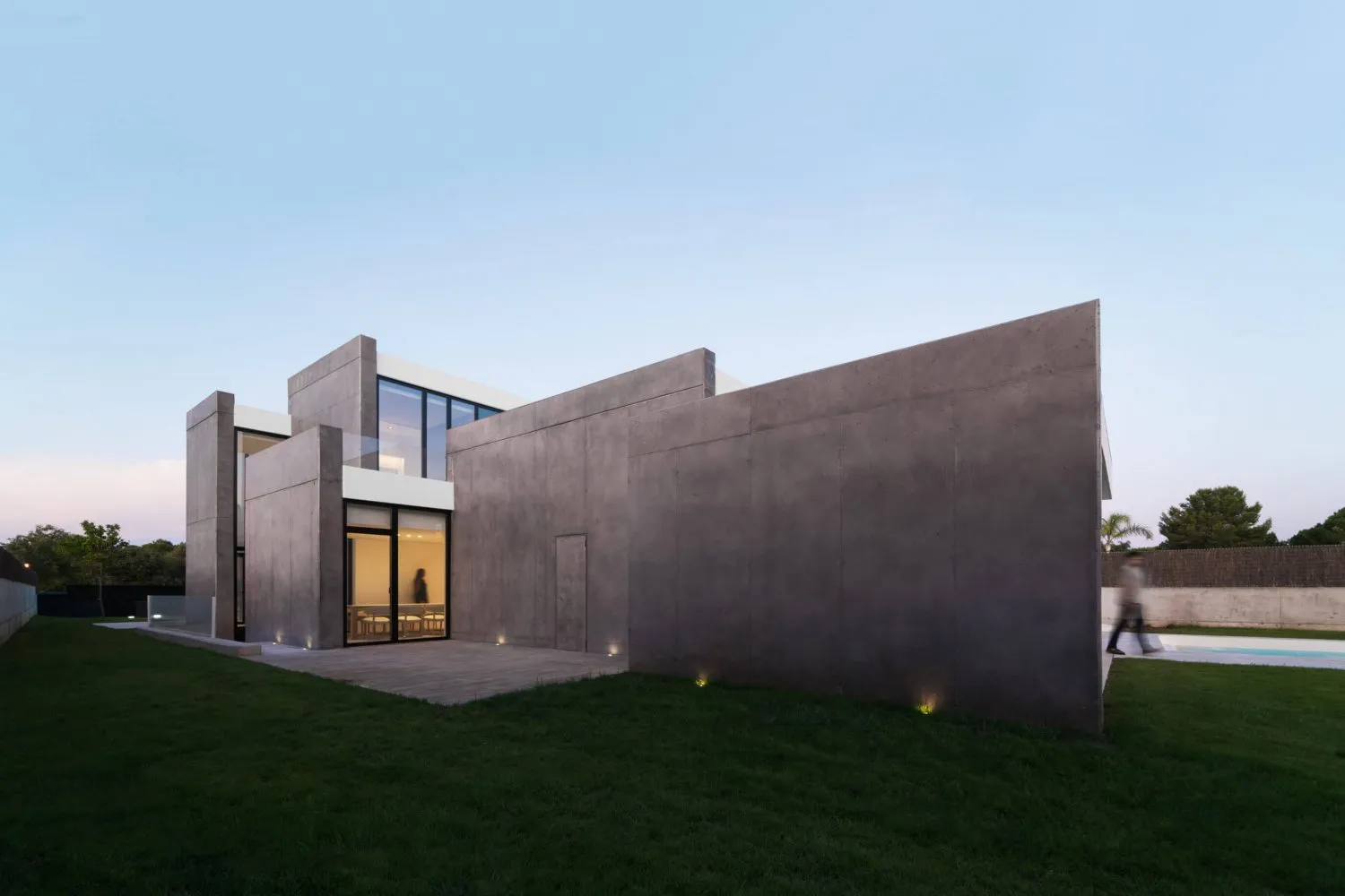 A modern residential home featuring a concrete exterior with large windows.