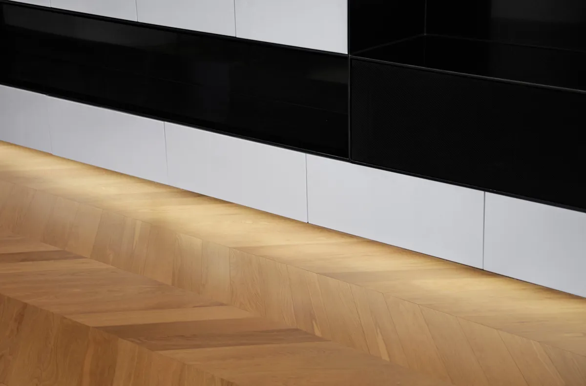 Modern living room featuring a wood floor with geometric patterns and white storage units.