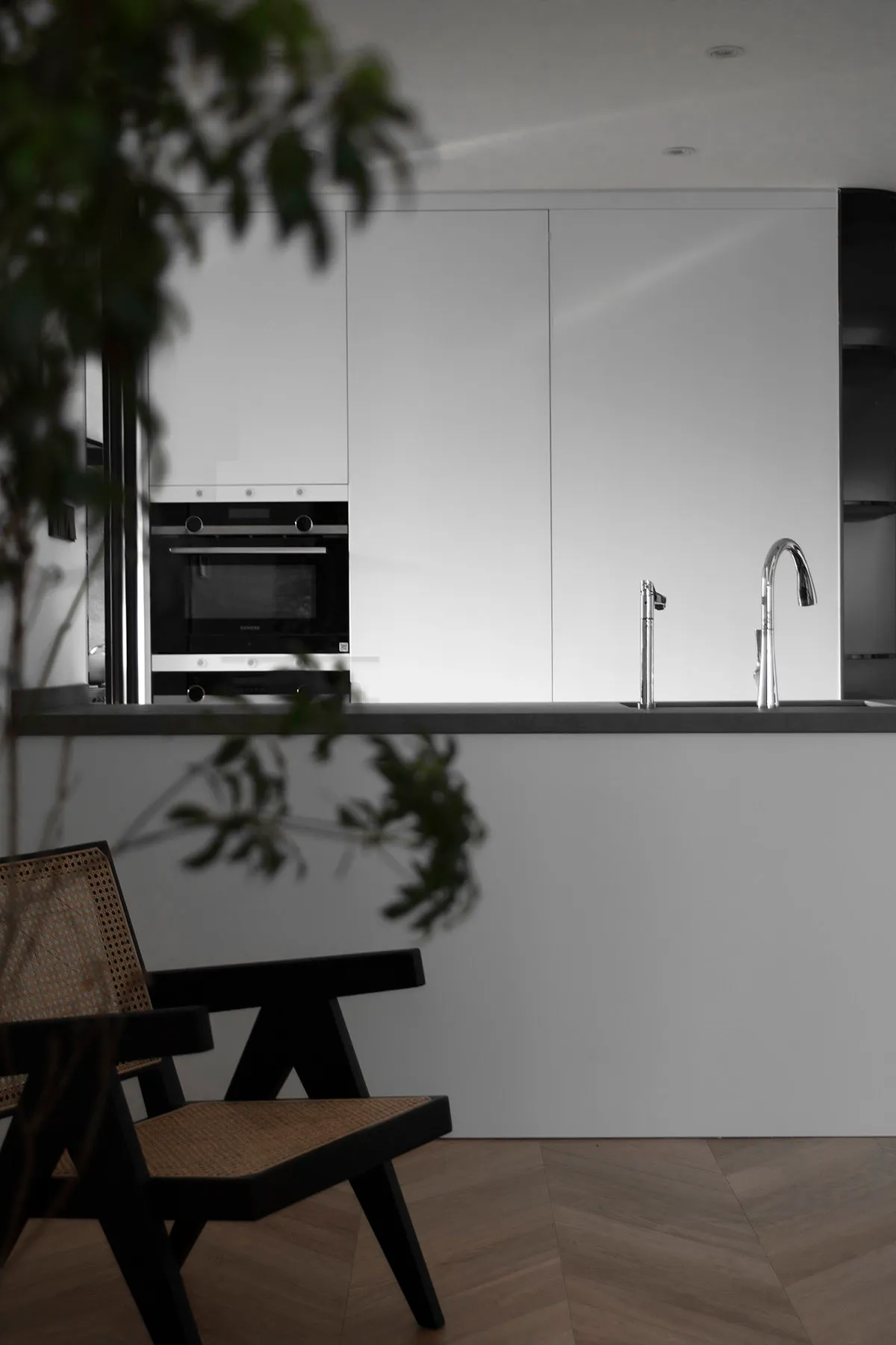 Modern minimalist kitchen with white cabinets, black kitchen island, and steel faucet.