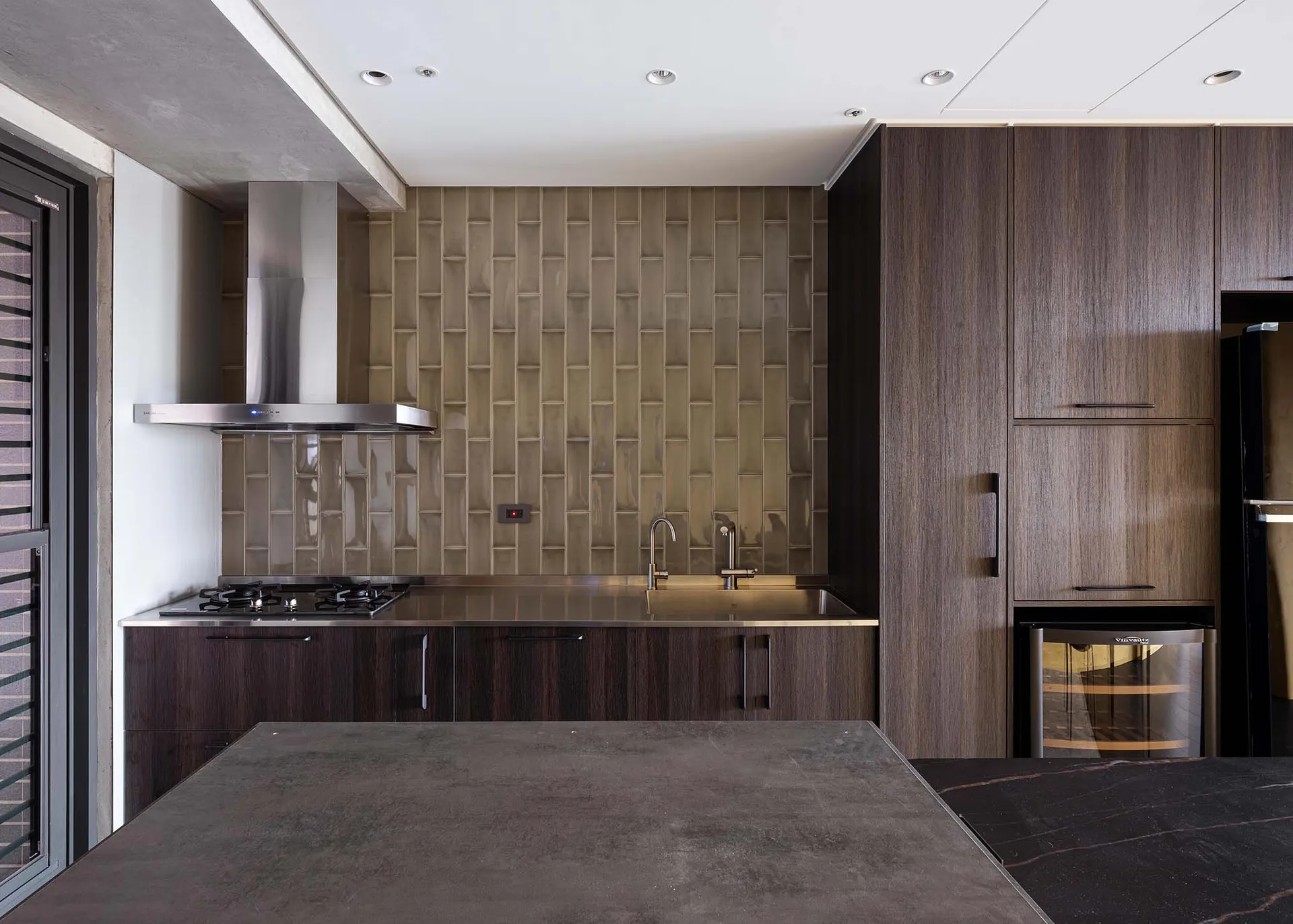 A modern kitchen with metallic surfaces, wooden cabinets, and glass backsplash.