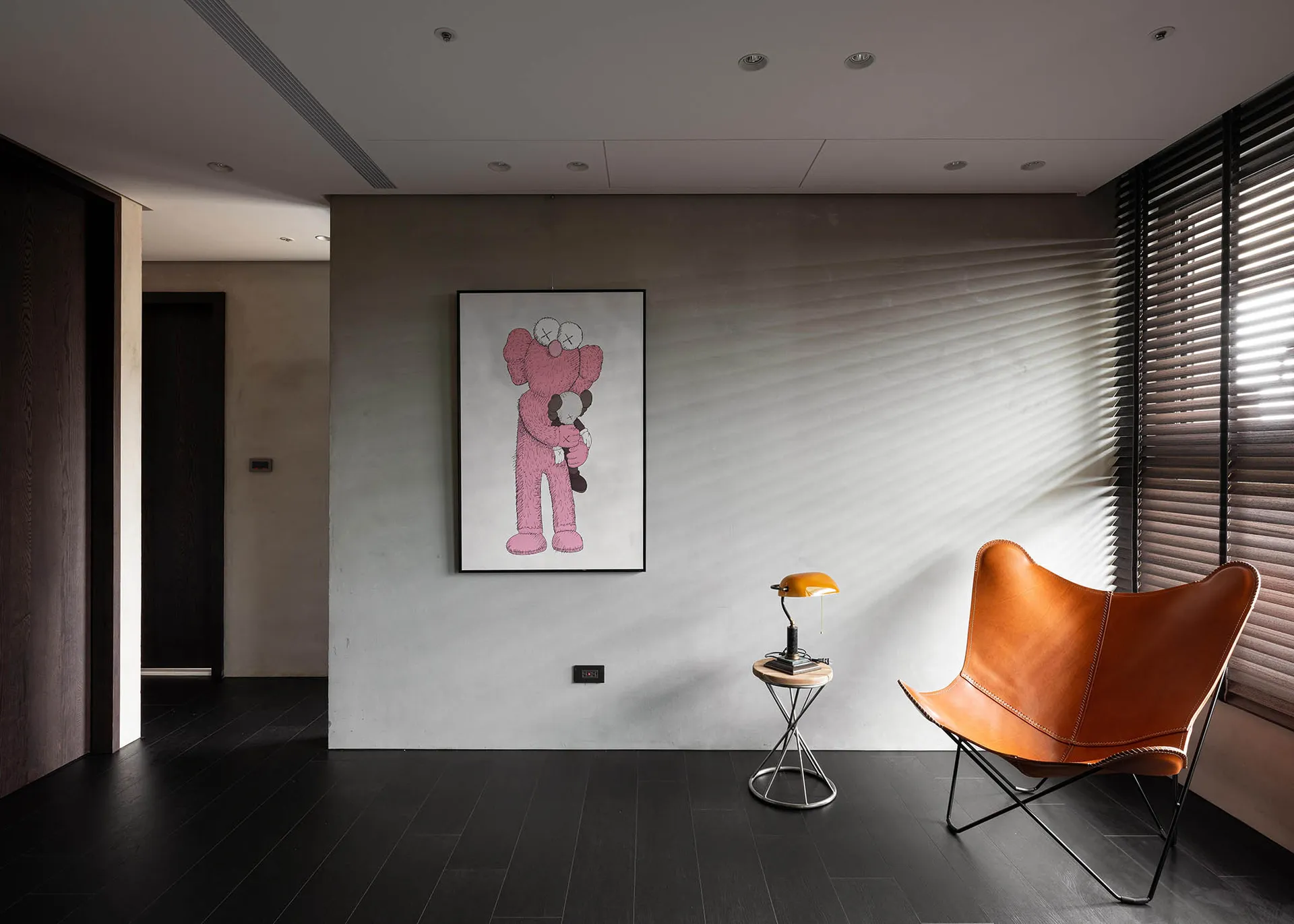 A modern living room with a concrete wall, featuring a large piece of artwork depicting a pink bear holding a smaller bear.