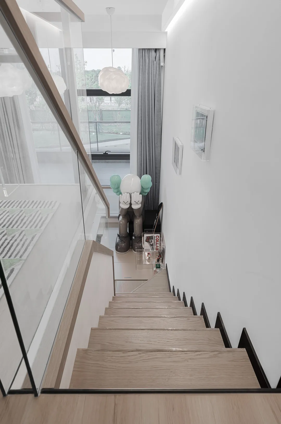 Modern minimalist staircase with wooden steps and metal railings, leading down to a lower level of a residential home.