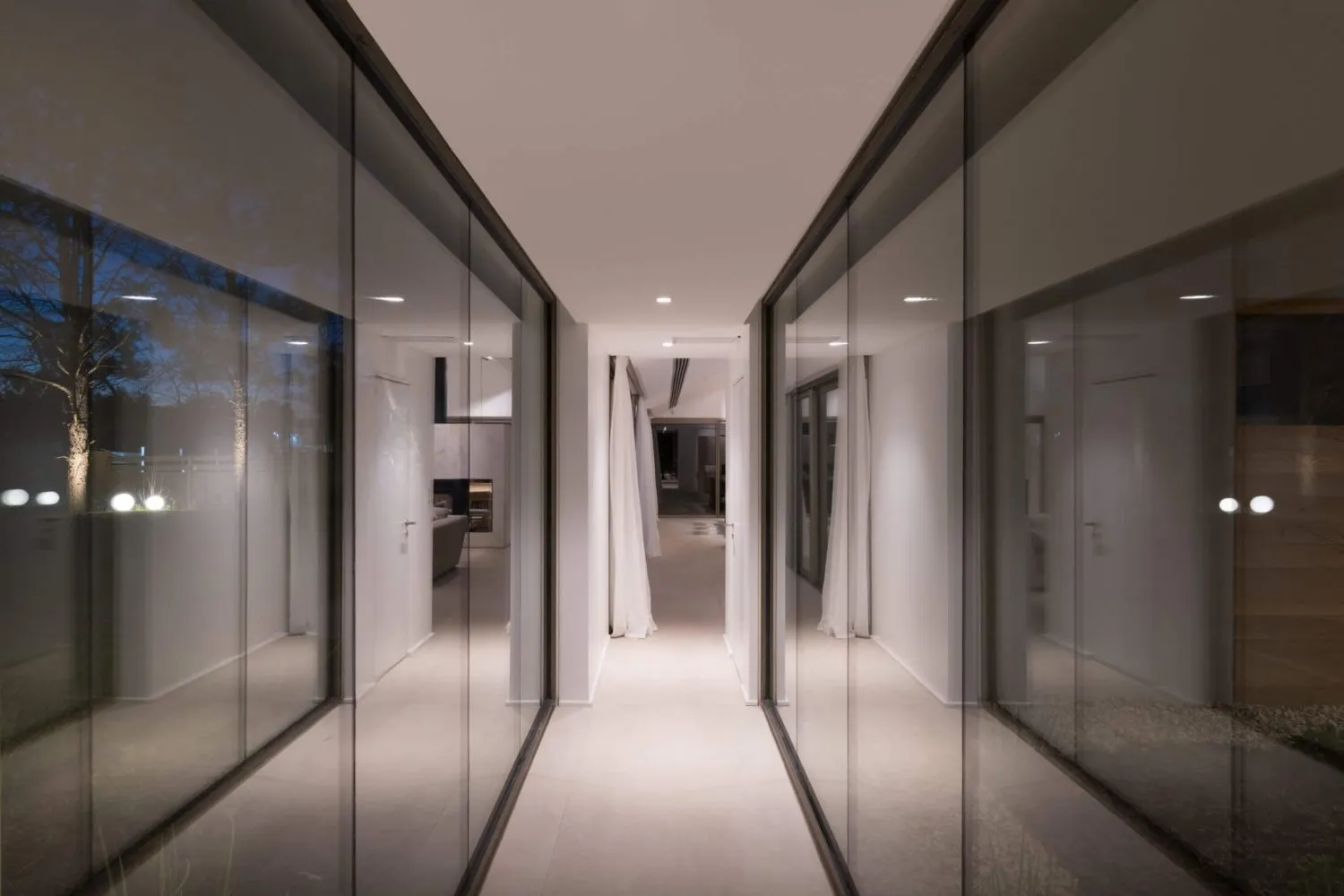 A modern hallway with glass walls and a long corridor.