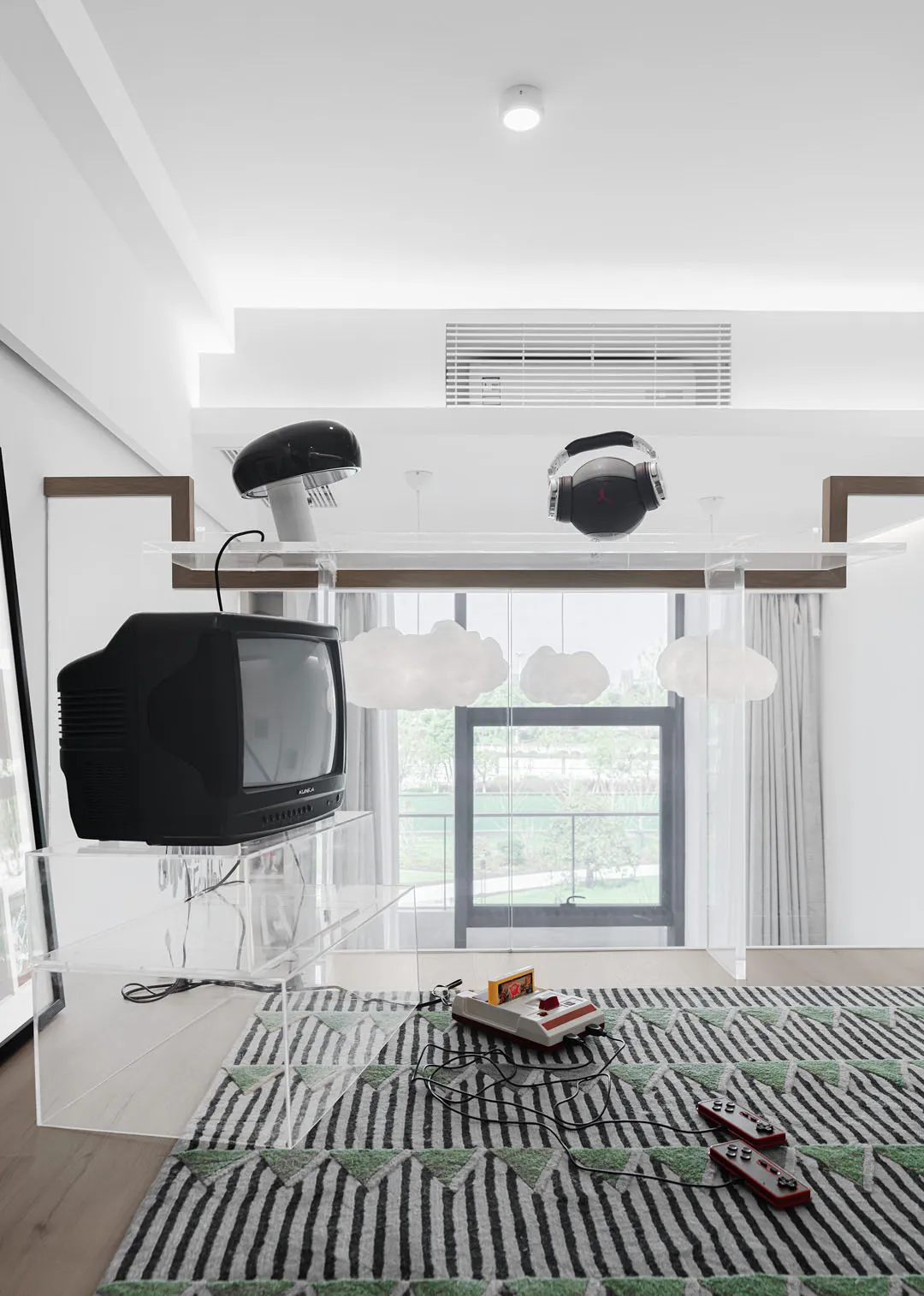 A modern living room with stainless steel furniture, a glass TV stand, and a patterned rug with clouds and stripes.