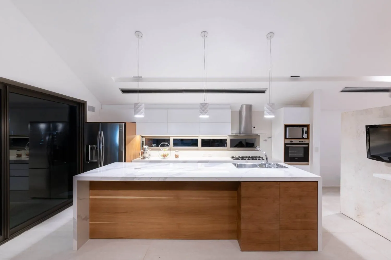 Modern residential kitchen featuring marble countertops, wooden cabinetry, and stainless steel appliances.