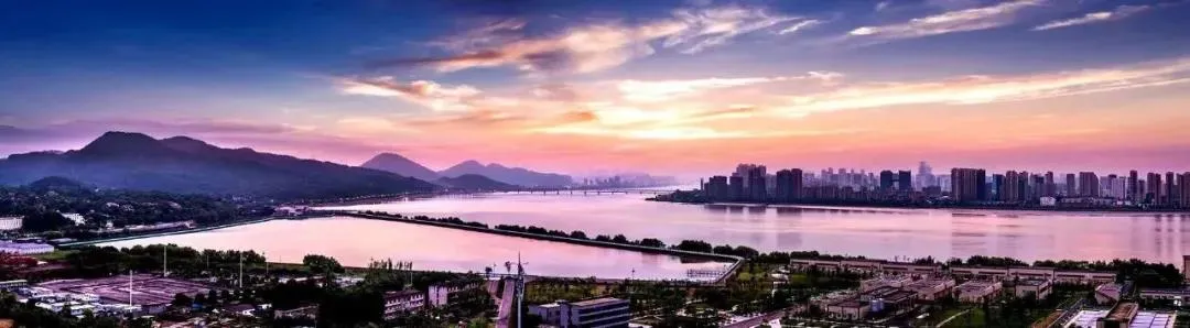 城市景觀全景,搭配大片水域與佈滿雲朵的天空。