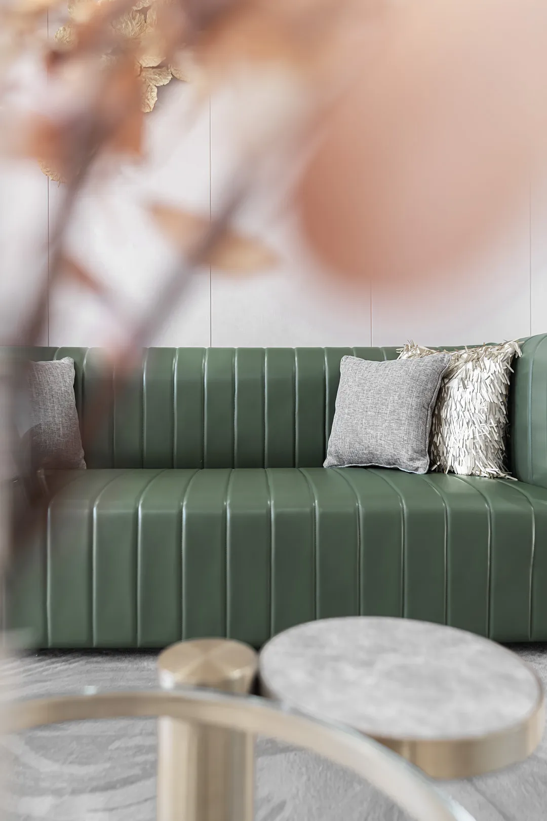 A modern green leather sofa with decorative pillows in a well-lit living room setting.