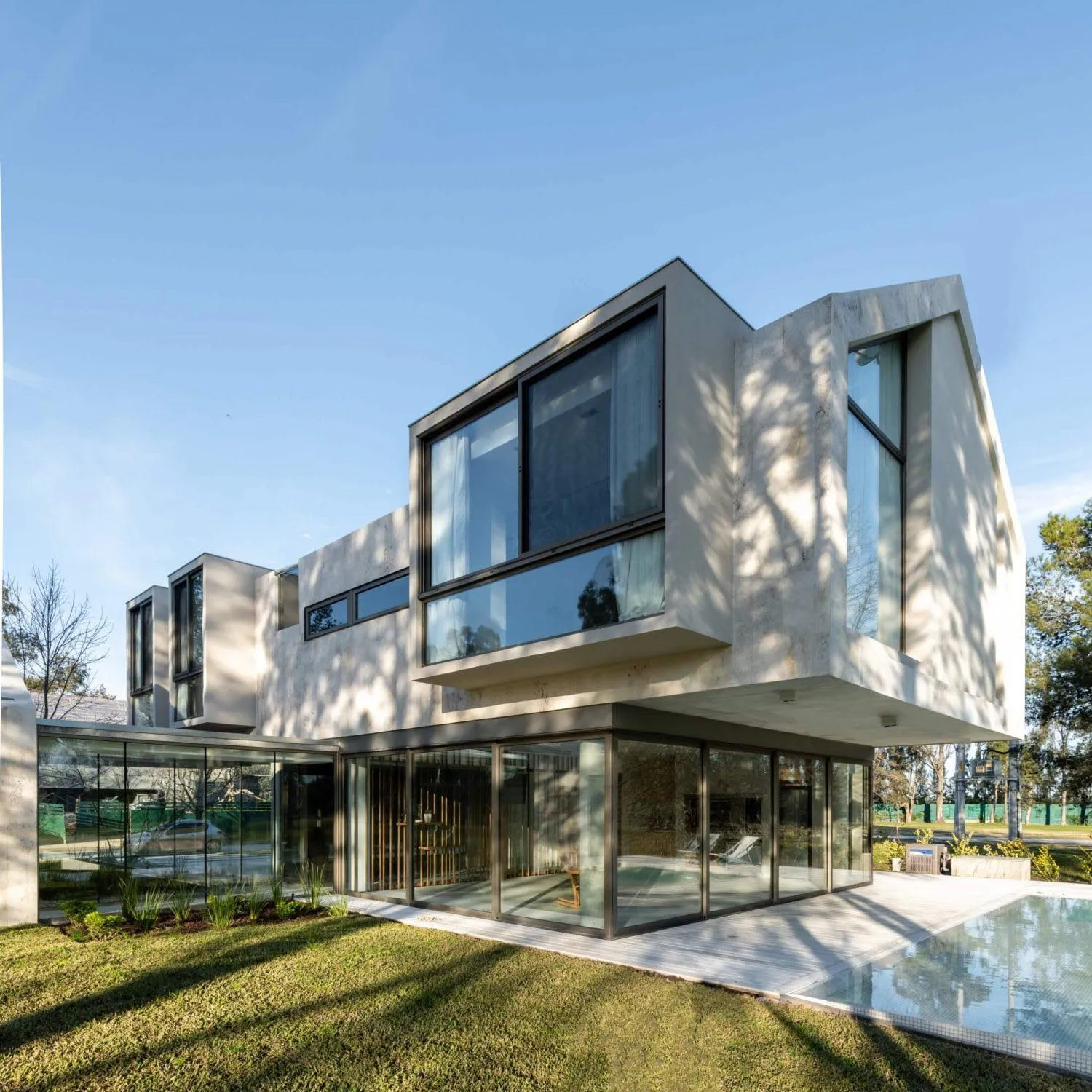 Modern house with concrete and glass exterior and large glass windows.
