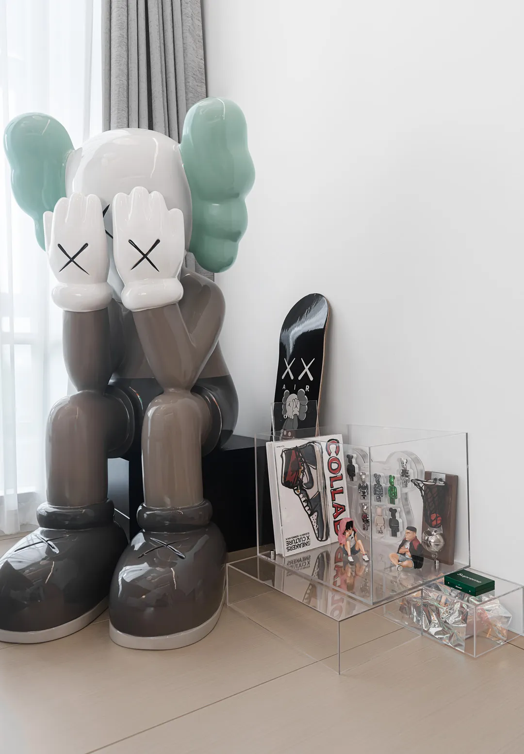 一間極簡風格的房間,展示一件現代室內設計藝術作品,包含一雙灰色與青綠色的大型 oversized 鞋子,旁邊