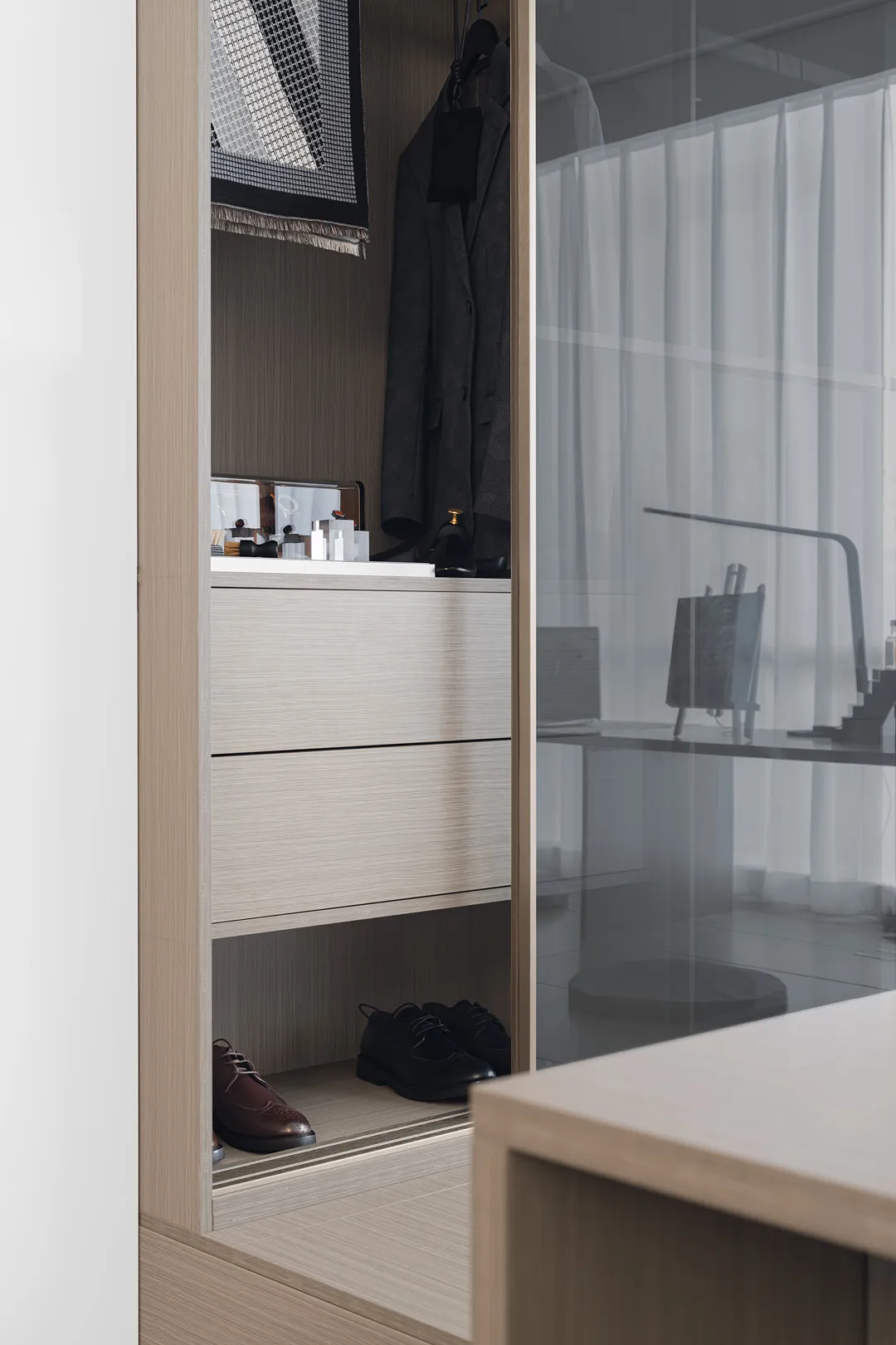 Modern minimalist closet featuring wooden shelves and a glass door.