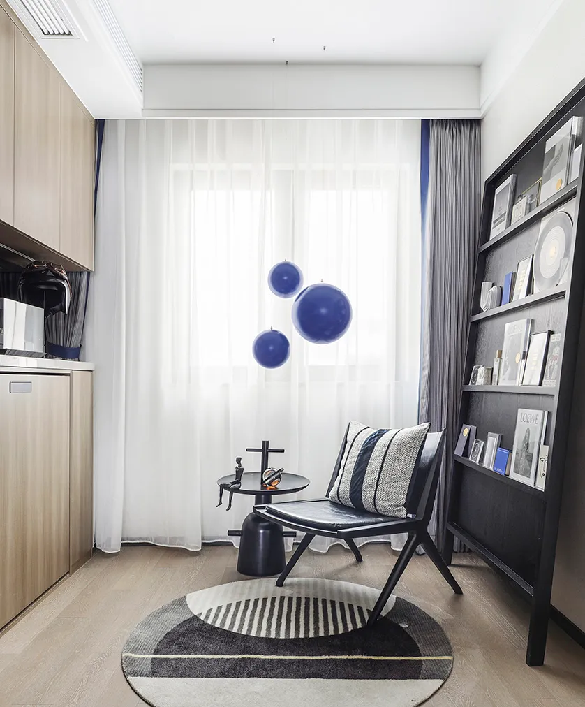 A modern minimalist living room with dark furniture, white curtains, and blue spherical decorations.