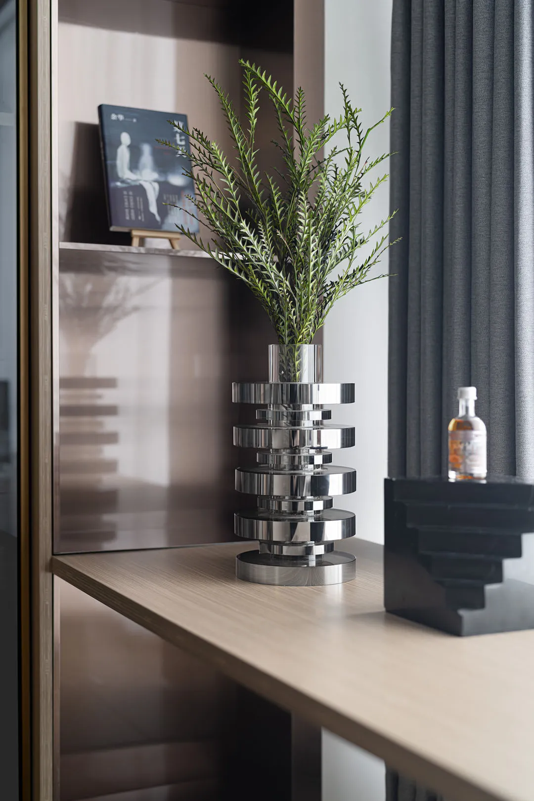 A minimalist living space adorned with a metallic botanical display on a wooden shelf.