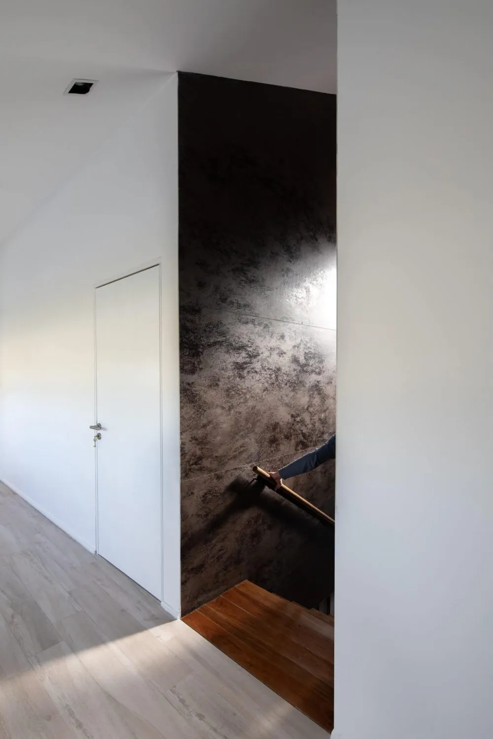 Modern minimalist interior featuring a stairway with wooden steps and a concrete wall