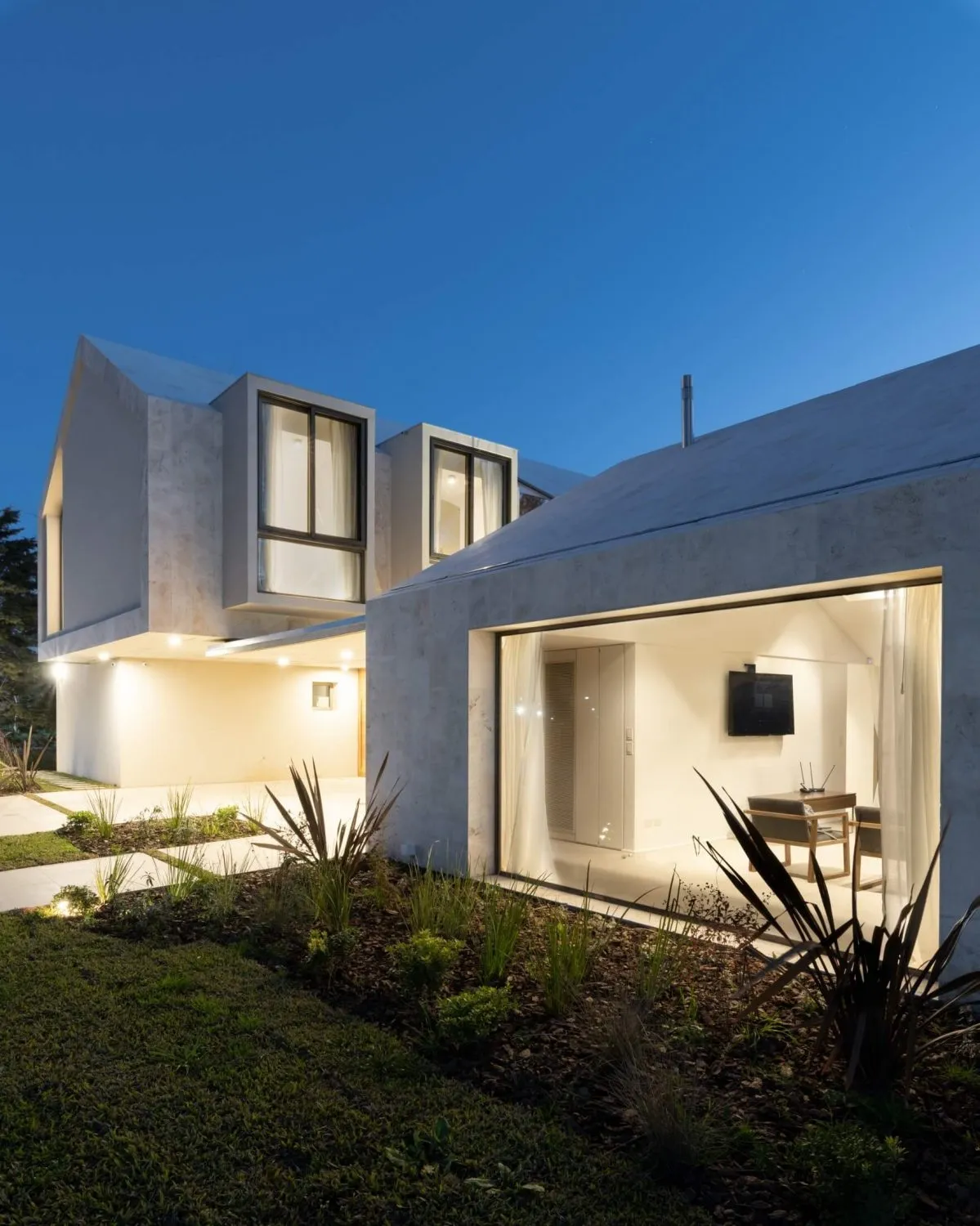 A modern residential exterior with concrete walls and illuminated windows.