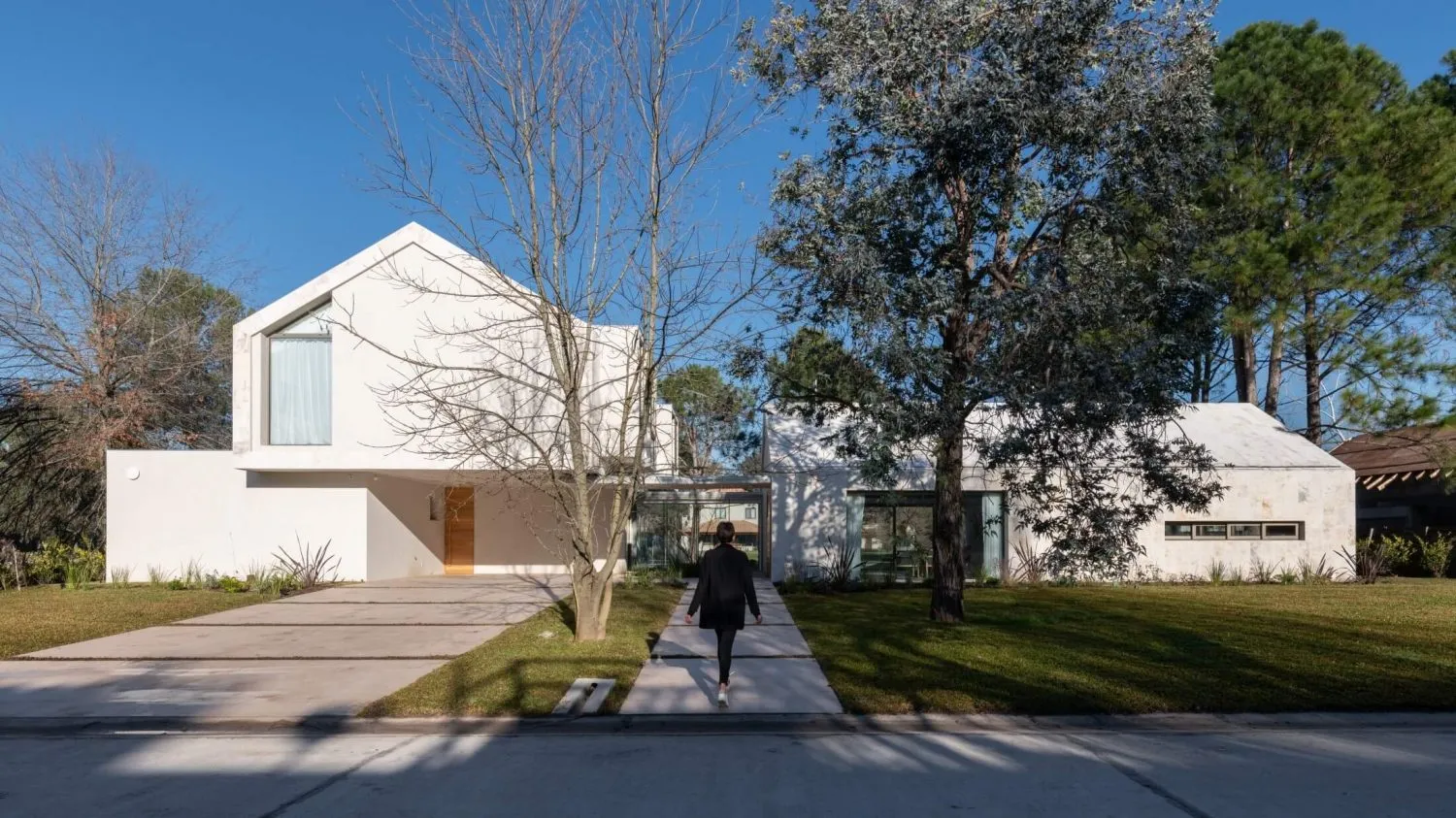 A modern residential building with white concrete exterior under a clear blue sky.