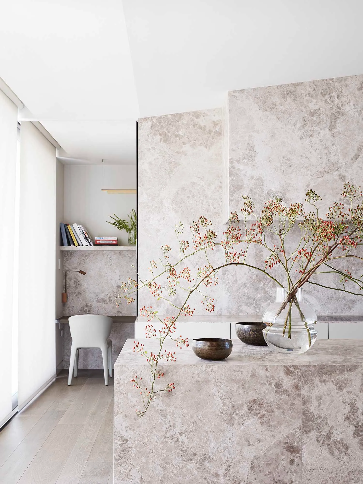 A minimalist living room with a marble accent wall and decorative elements.