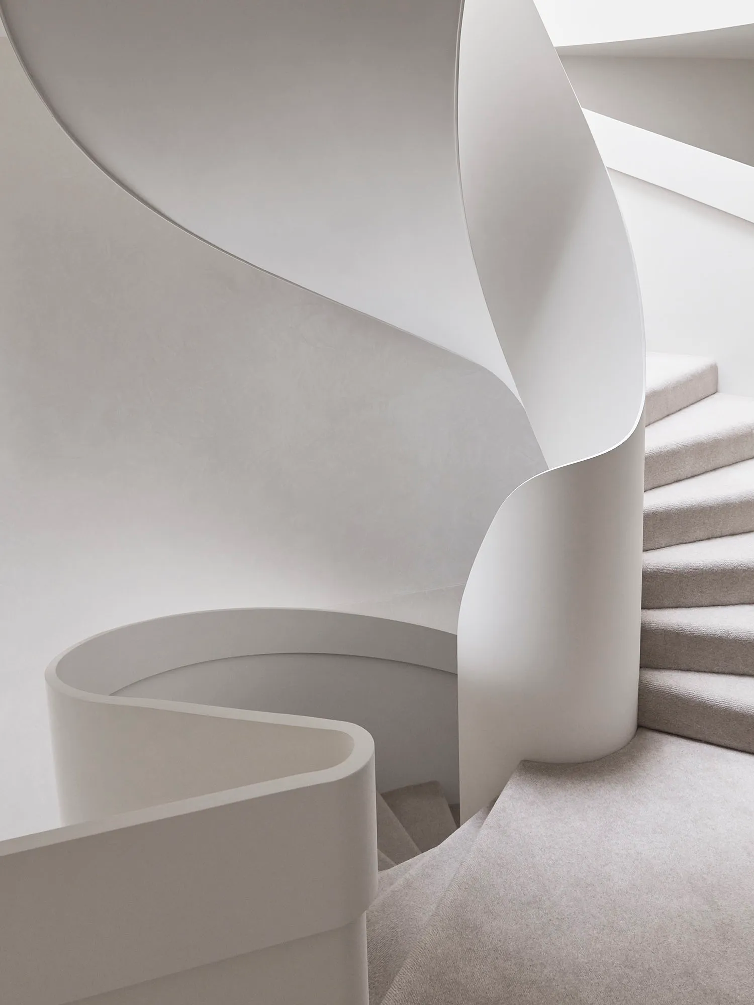 一座現代白色螺旋樓梯,搭配光滑曲面牆與柔軟中性色地毯。