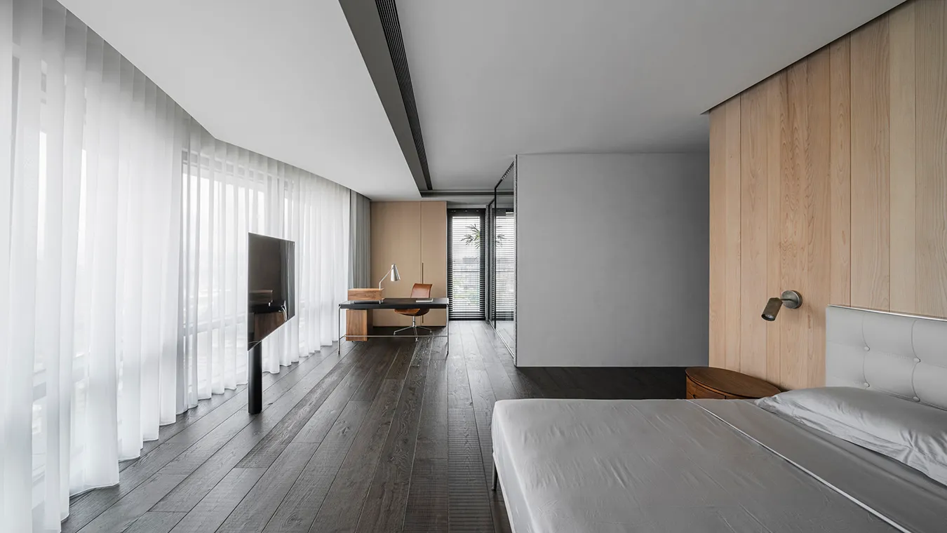 Modern bedroom featuring dark wooden floor, white curtains, and minimalist furniture.