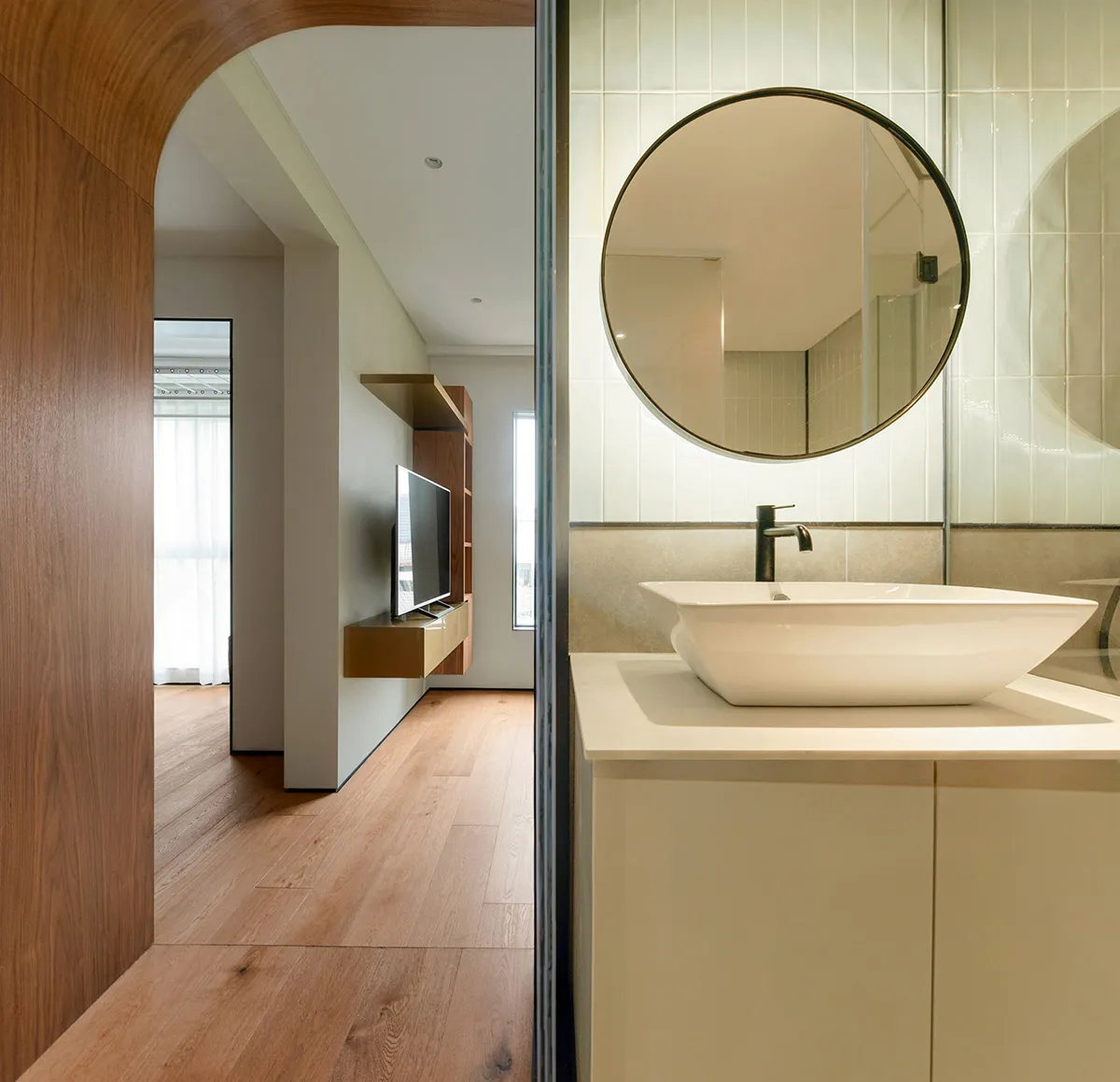 A minimalist bathroom featuring white tiles, a modern sink, and wooden flooring.
