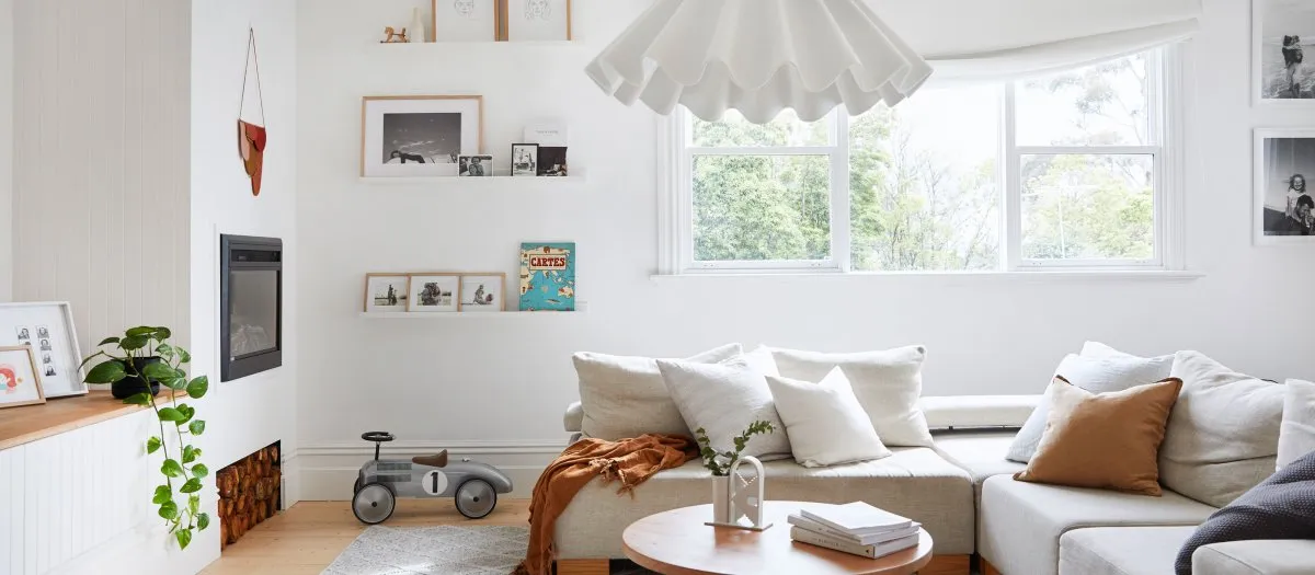 A minimalist living room with a fabric couch, wooden floor, and decorative elements.