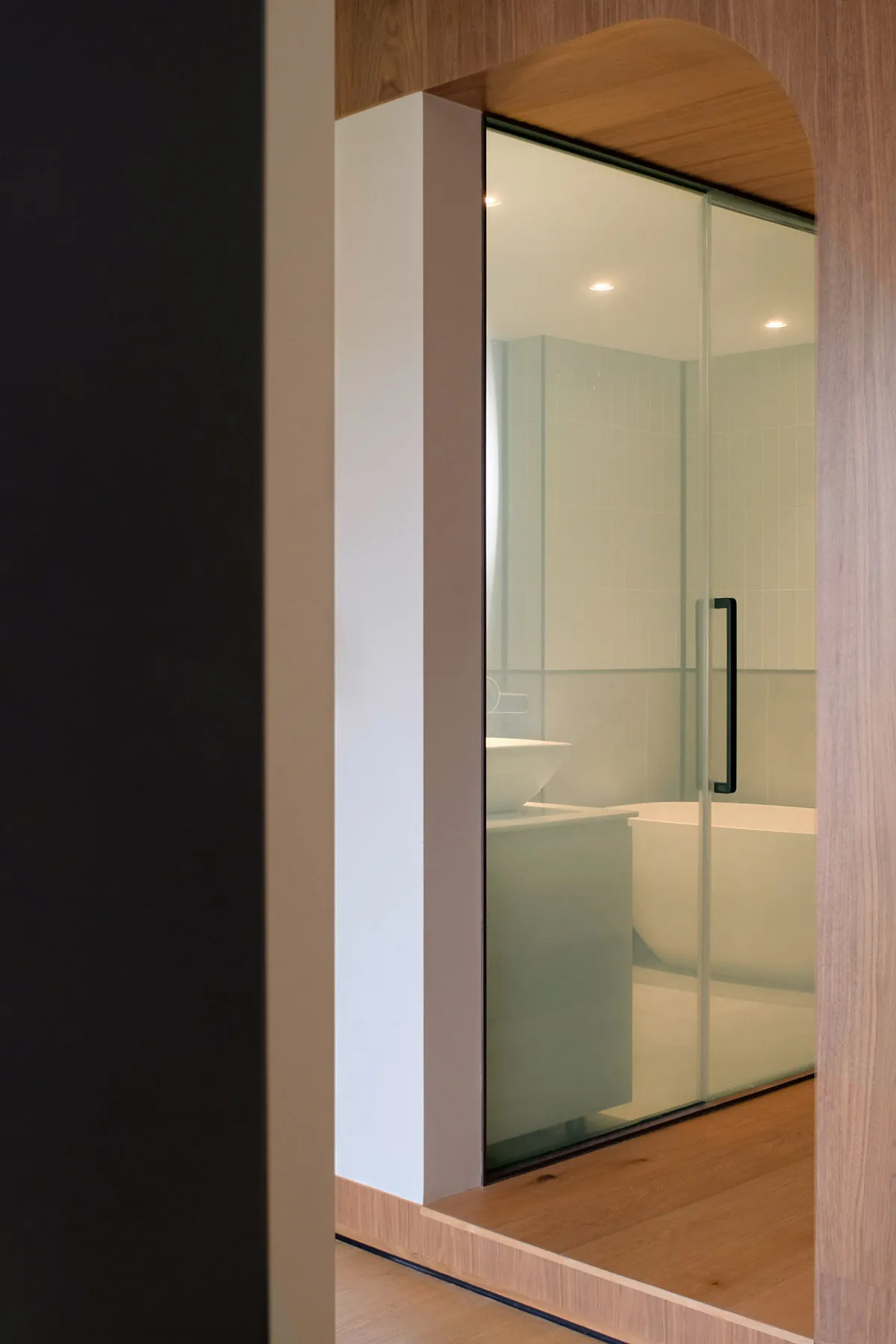 Modern bathroom with glass door and minimalist design.