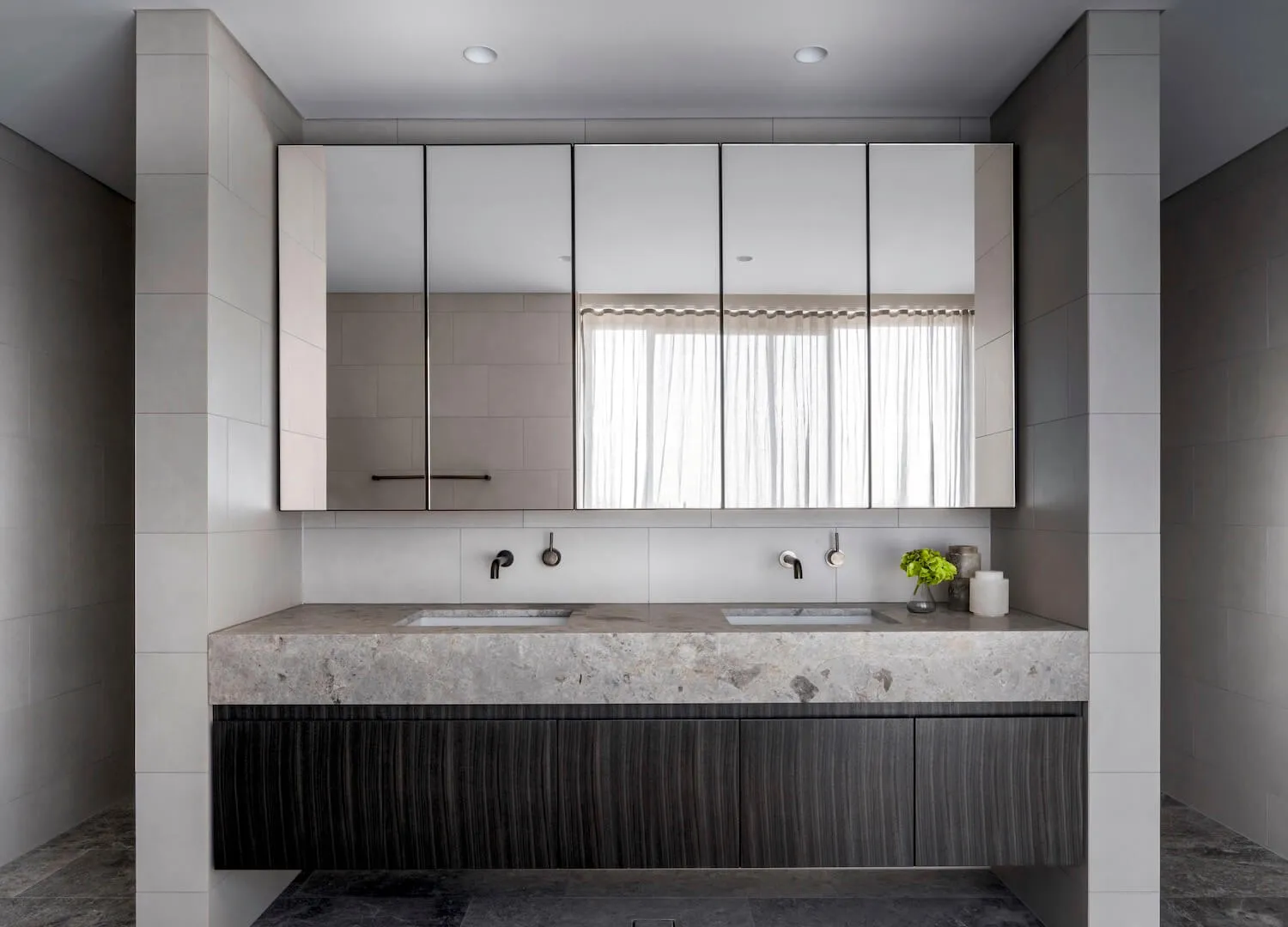 Modern bathroom with marble countertop and wooden cabinets.