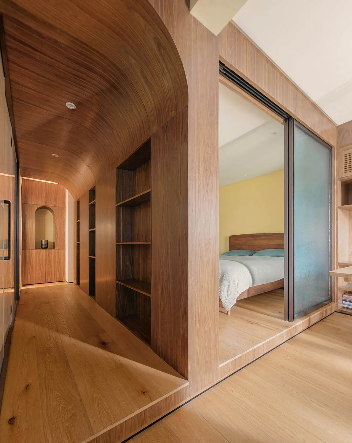 A modern bedroom with wooden walls and a wooden bed frame.