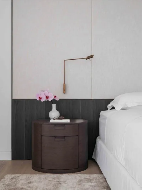 Modern bedroom featuring a wooden nightstand with a vase of flowers and a lamp.