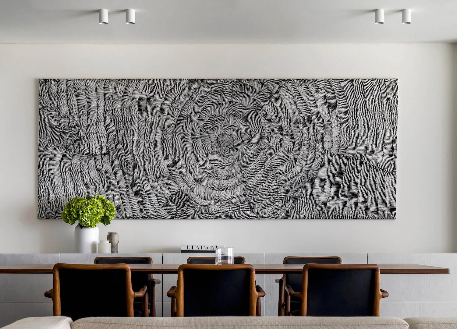 A modern interior space featuring a large abstract wall art with concentric circular patterns.