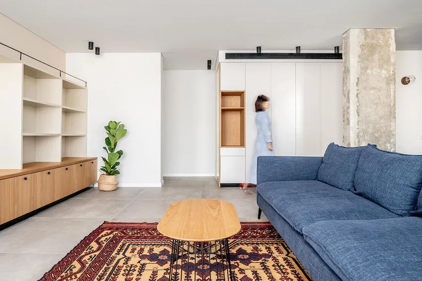 A modern living room with a blue sofa, wooden coffee table, and fiddle leaf fig plant.