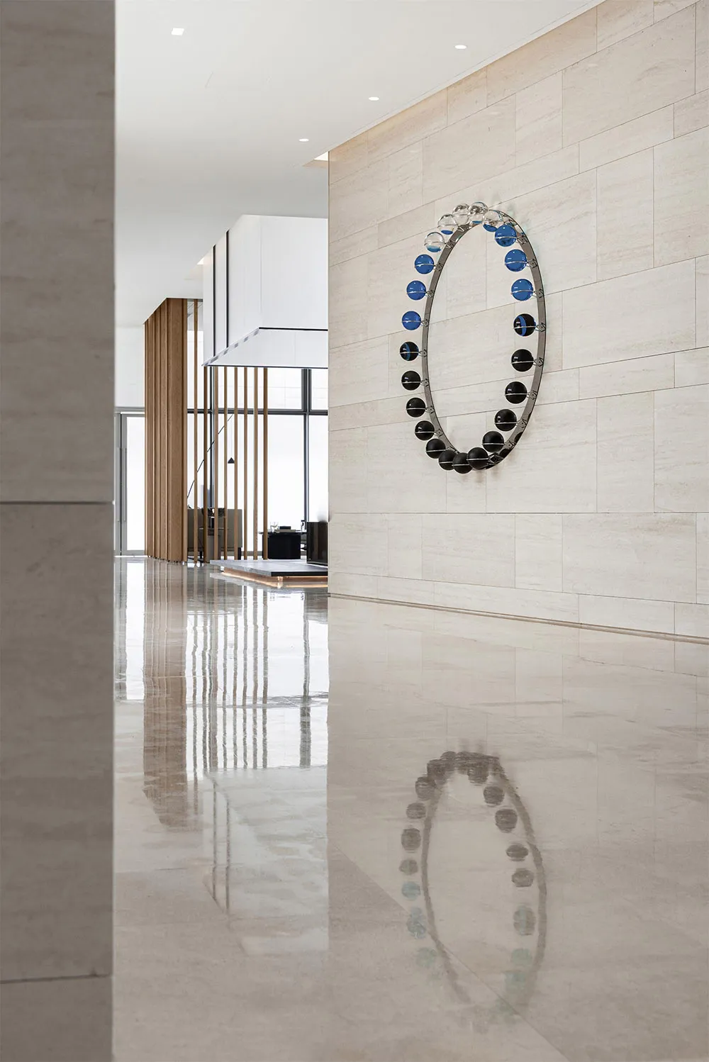A modern lobby featuring a glass circle sculpture on a beige tiled wall.