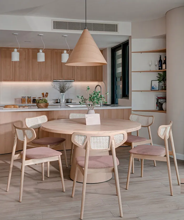 A modern residential kitchen dining area showcasing a wooden table and chairs, with a wooden pendant light hanging above and