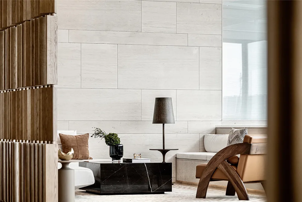 A modern living room with white concrete walls, a black marble coffee table, and a wooden armchair.