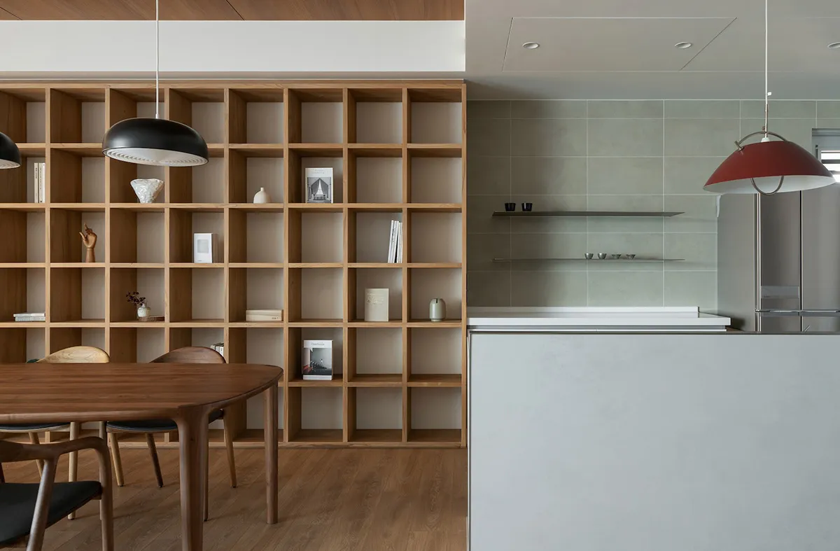 A modern kitchen and dining room with wooden furniture, concrete walls, and metal accents.