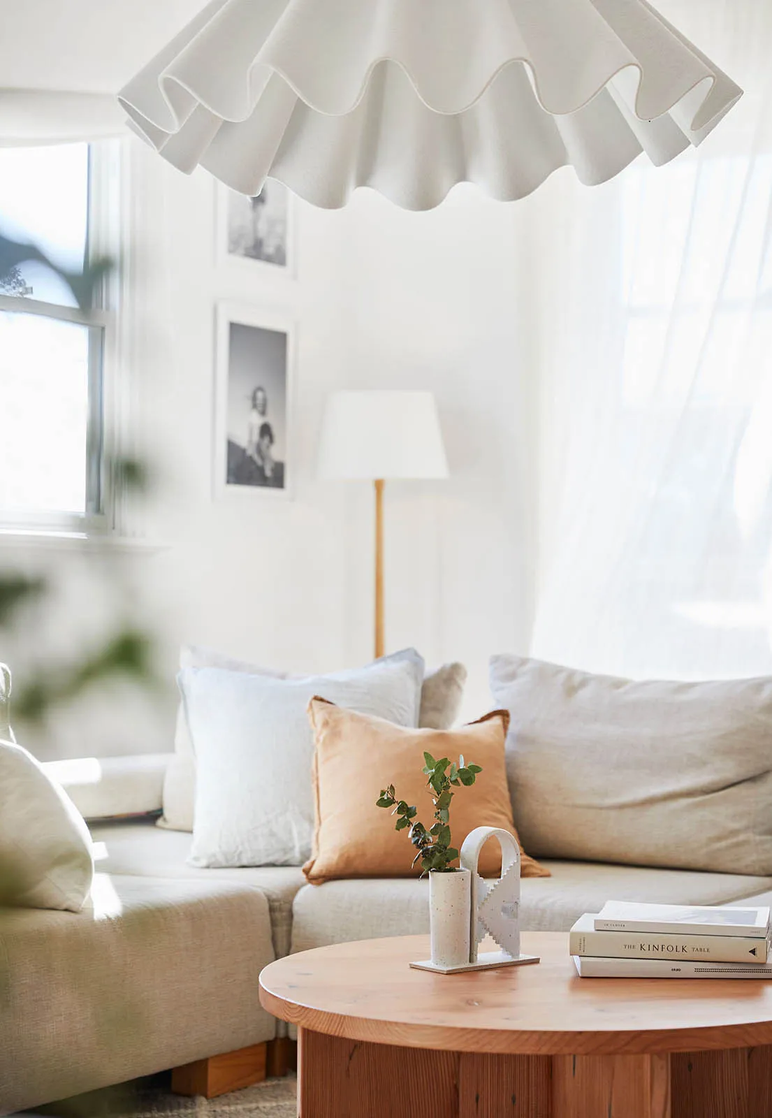 A minimalist living room featuring a light-colored fabric sofa, round wooden coffee table, and decorative elements like a fri