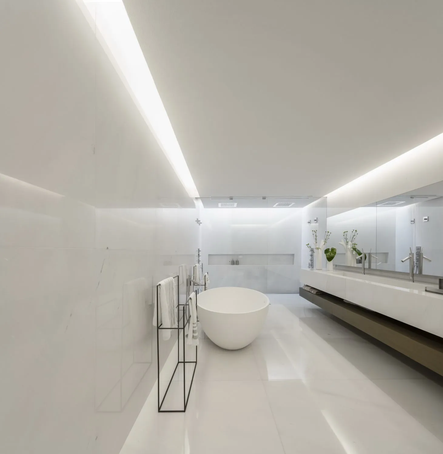 Modern minimalist bathroom with white marble fixtures and a round freestanding bathtub.
