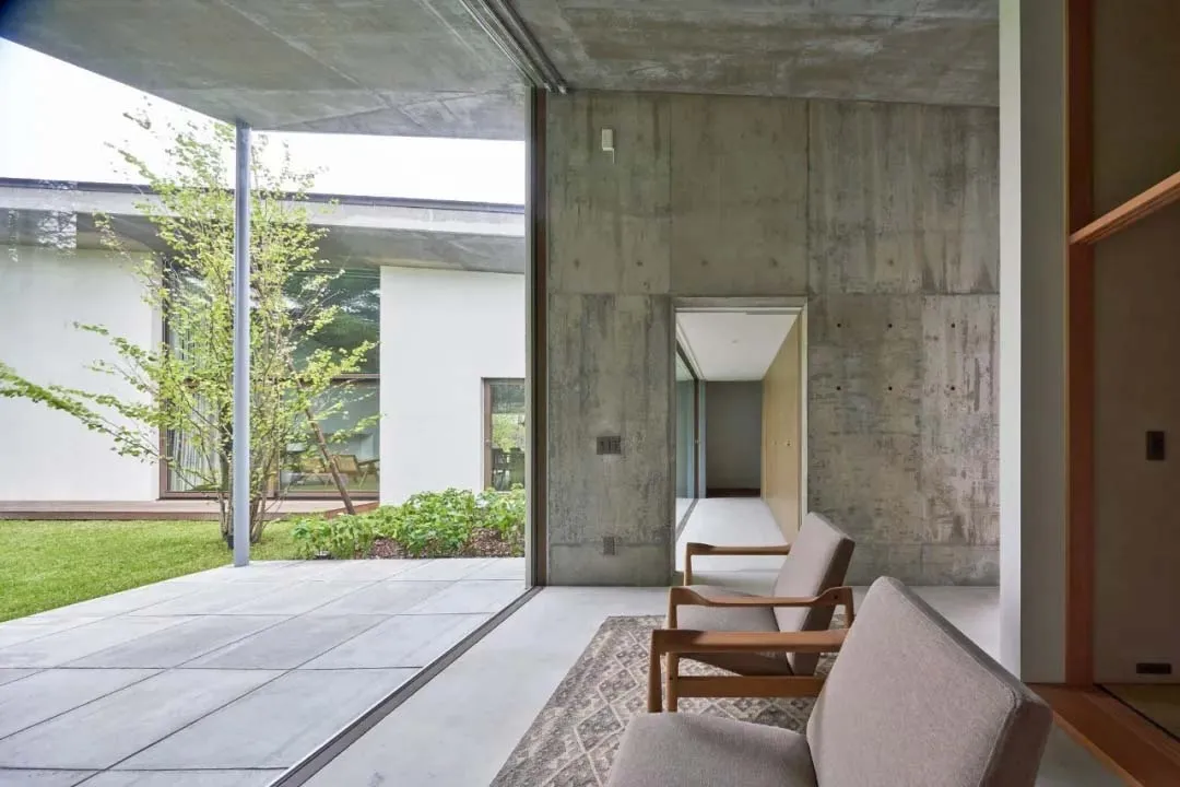 A minimalist living space featuring concrete walls and furniture in a modern, open-concept design.