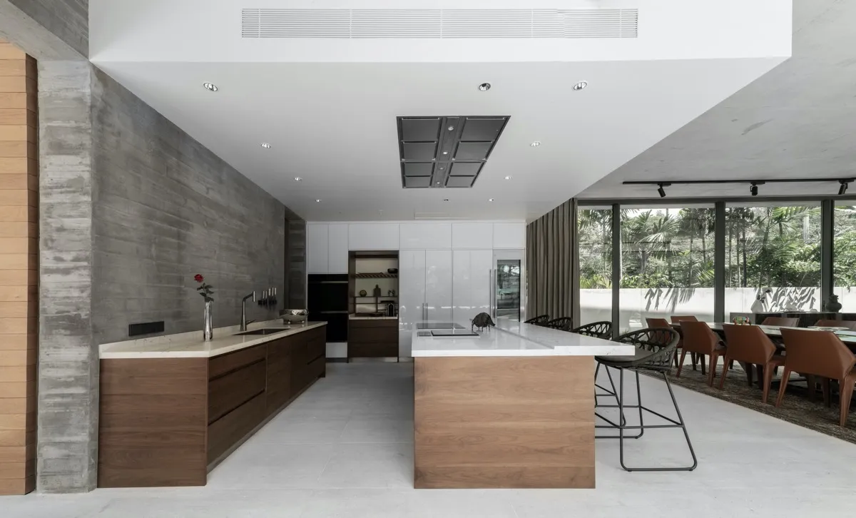 Modern kitchen with wooden countertops, concrete walls, and a large dining area.