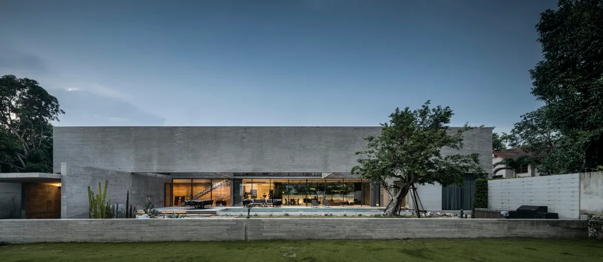 A modern residential house with a minimalist design, featuring a concrete exterior and a large pool in the yard.