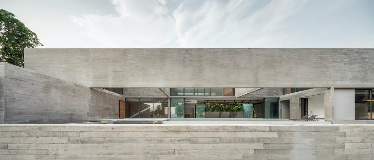 Modern, minimalist house with concrete exterior and large windows.