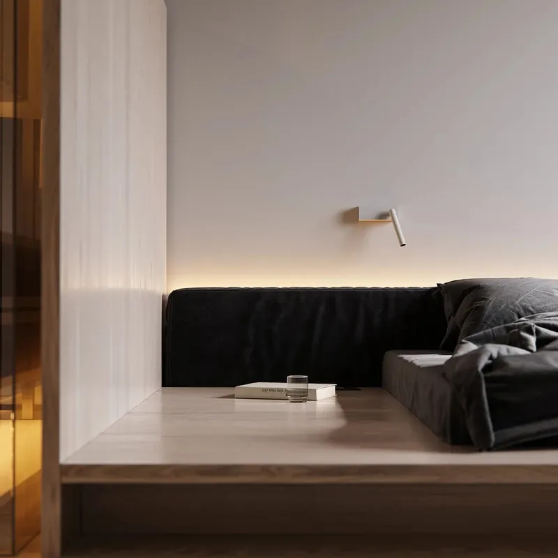 Black textured sofa in a minimalist space with ambient lighting and a simple wooden platform.