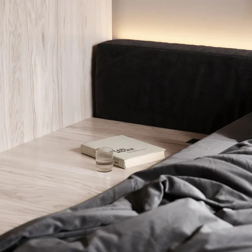 Modern bedroom scene featuring a minimalist bedside nightstand with matte materials and sleek design.