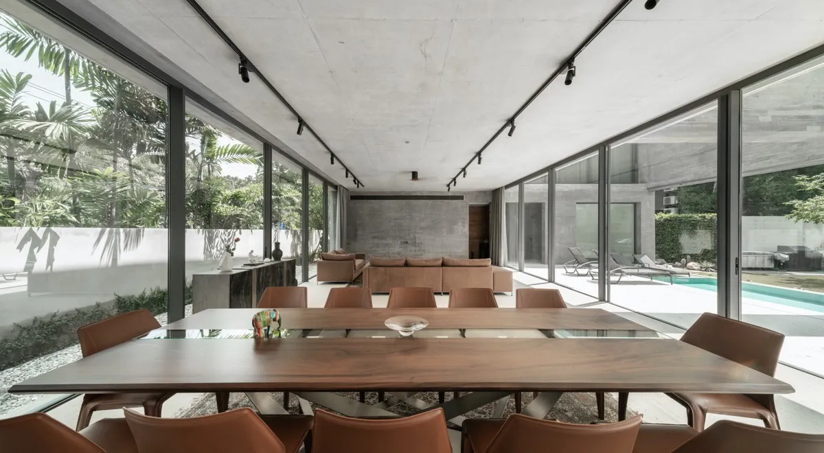 Contemporary dining room with concrete, glass, and leather materials and a large table.