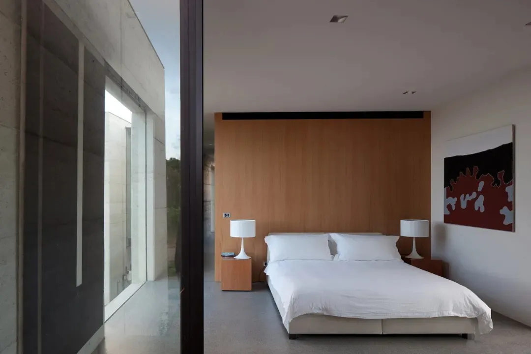A modern bedroom with a wooden wall, white bedding, and white lamps on nightstands.