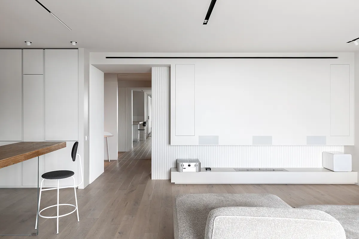 Modern minimalist living room with white cabinets, wooden flooring, and a white couch.