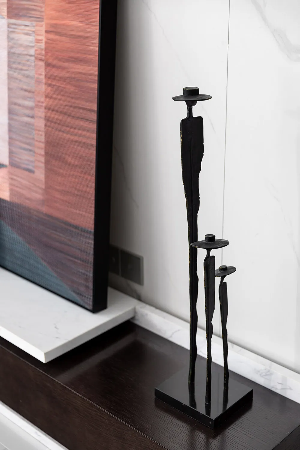 A minimalist metal sculpture featuring a tall, sleek, and simplistic design.